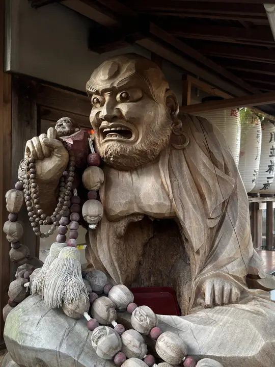 Carved wooden figure holding prayer beads